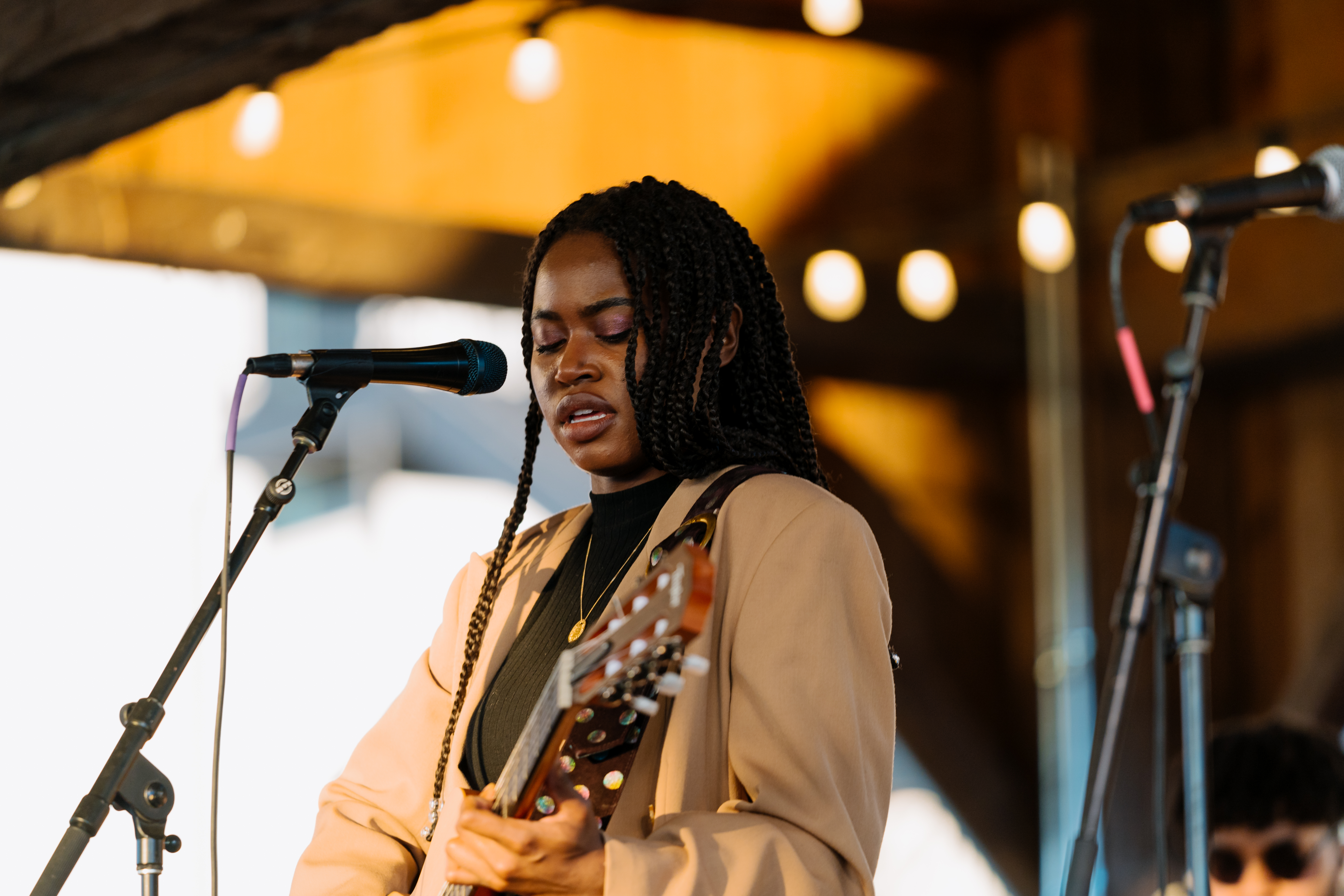 A singer performing on stage at the Silos, playing the guitar.