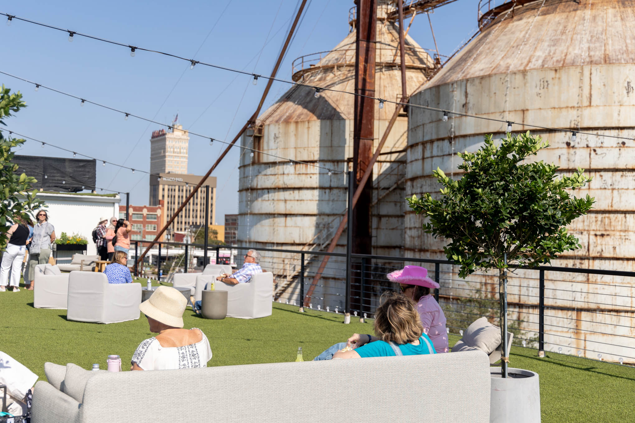 Scene of the Magnolia Market rooftop lounge. People are scattered around the rooftop's seating.