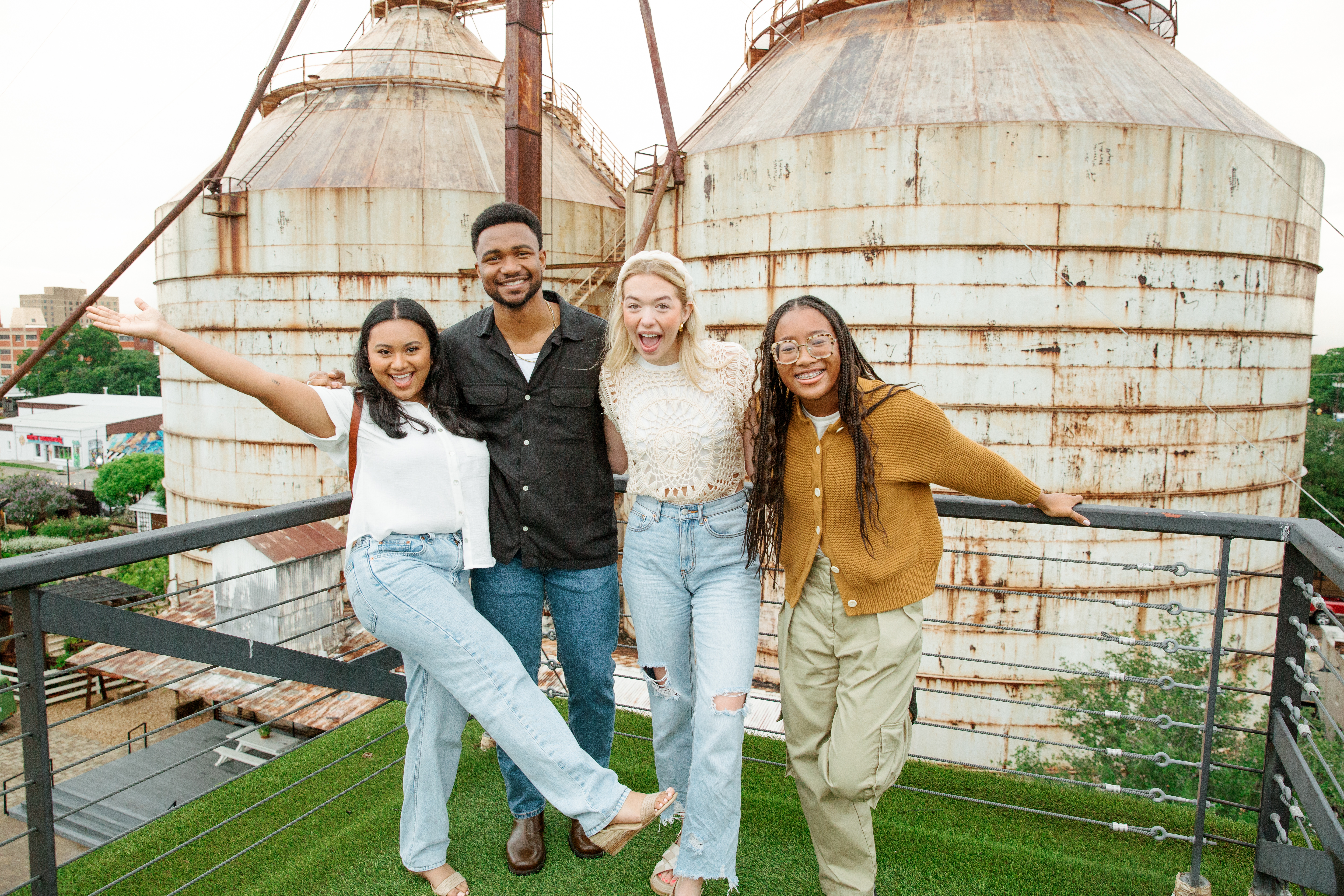 4 people standing and smiling atop the roof at the Magnolia Market.