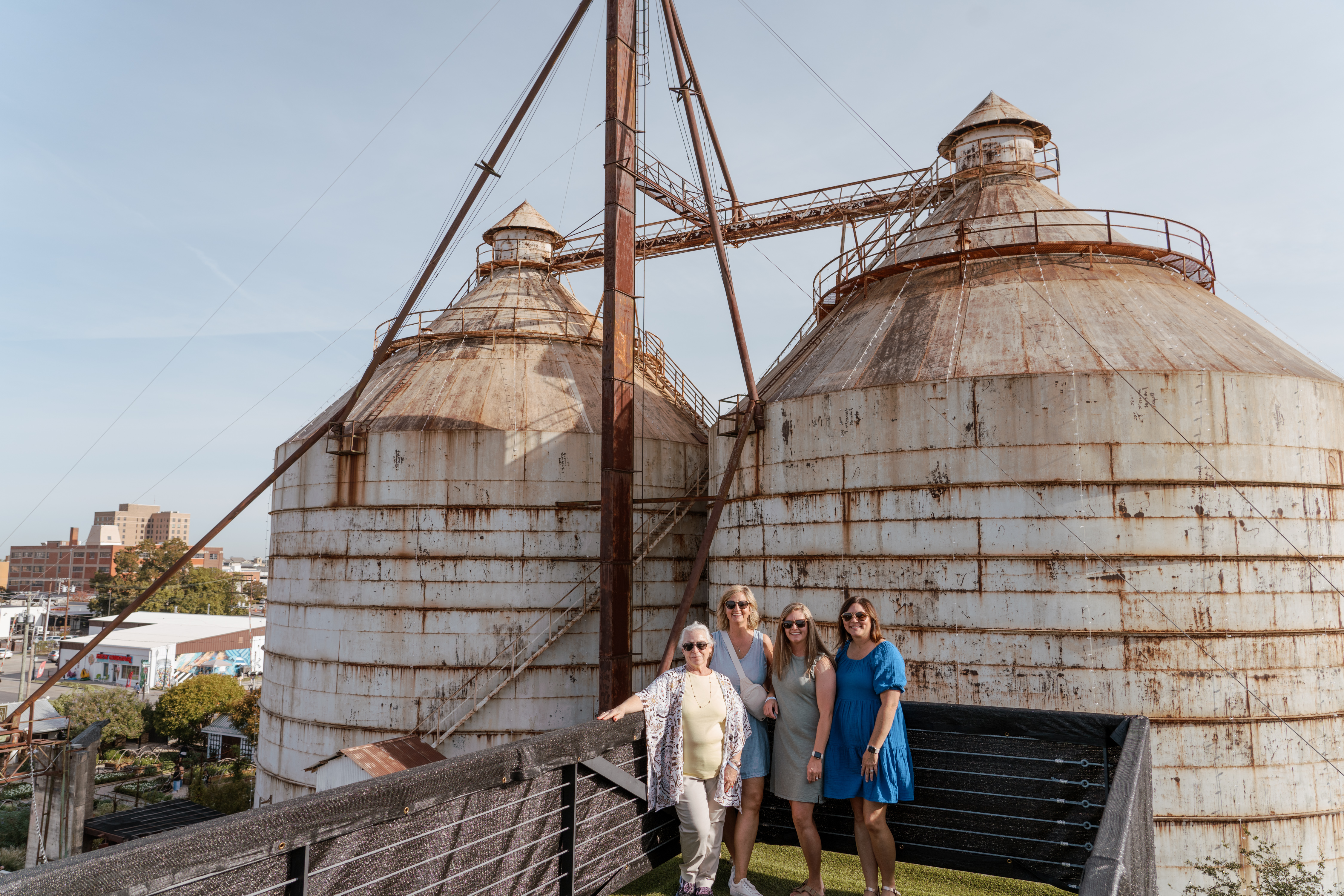 4 people standing and smiling atop the roof at the Magnolia Market.