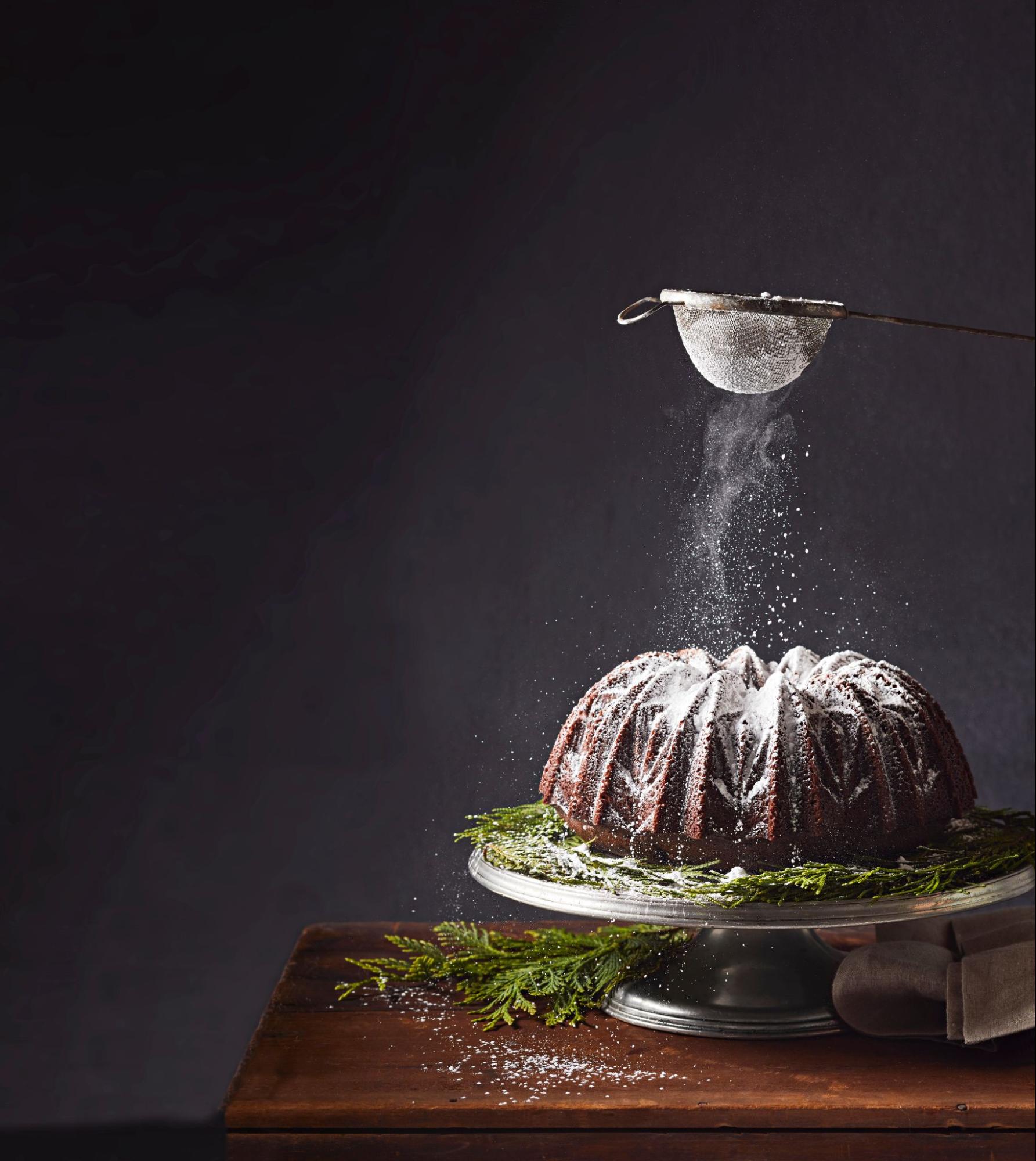 Chocolate bundt cake dusted with powdered sugar on cake stand