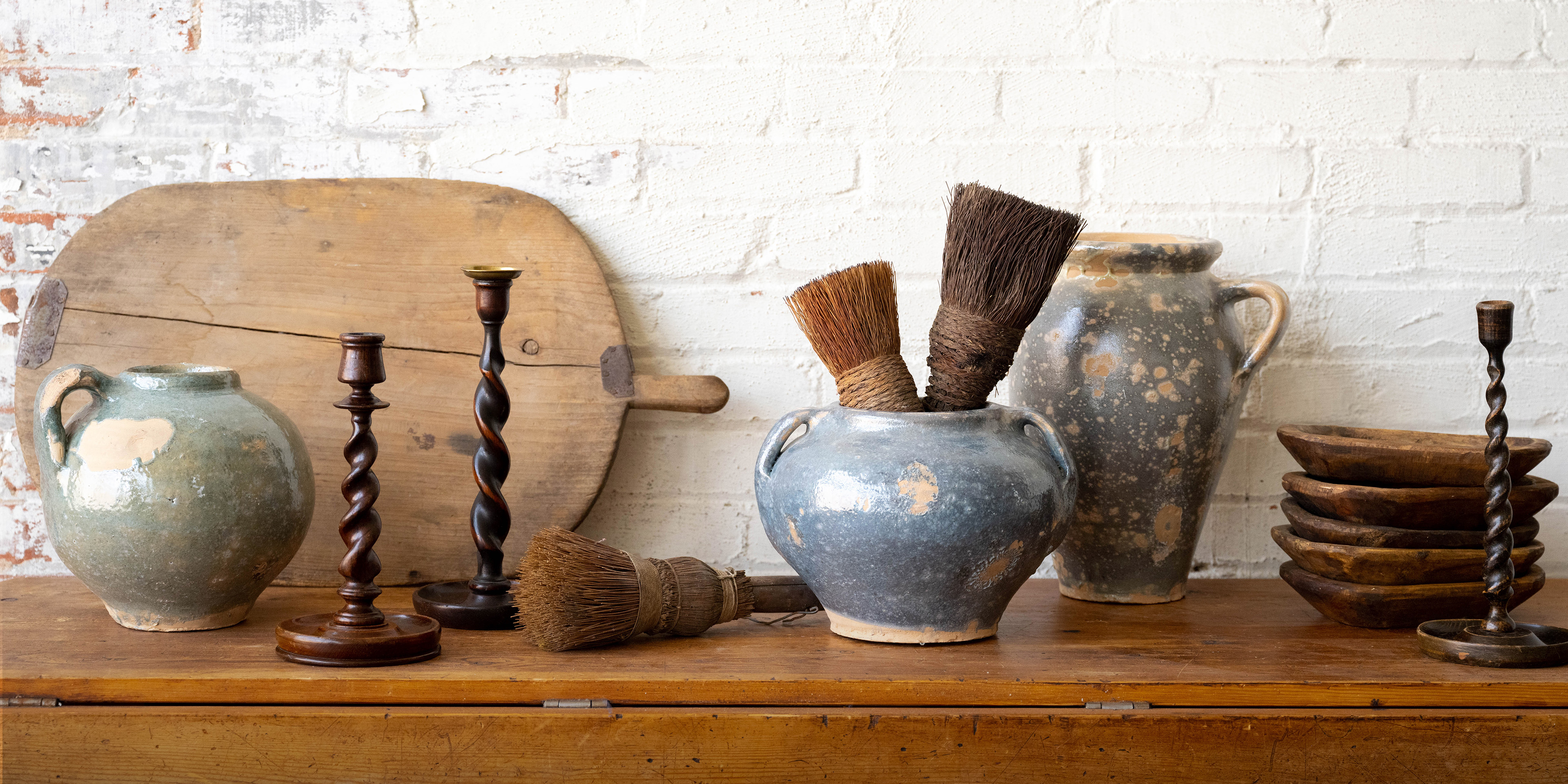 a table with found and collected pots, candlesticks, and bread boards