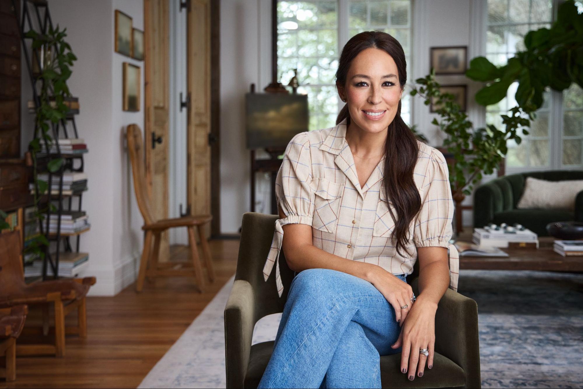 Joanna Gaines smiles while sitting in a chair.