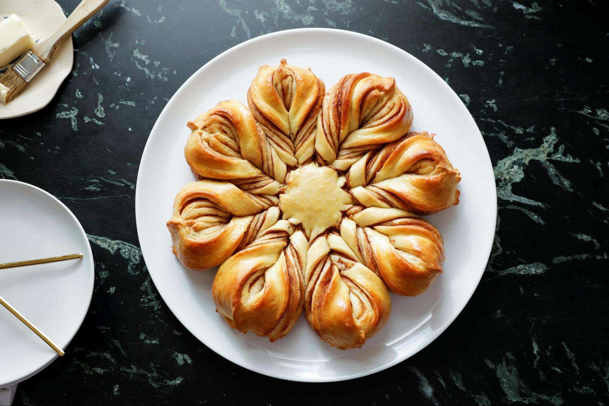 Star bread on a white plate against a black counter.