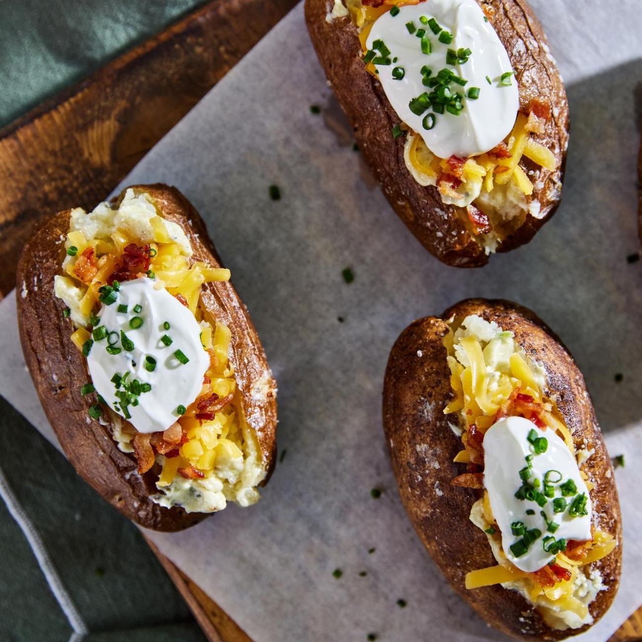 Three loaded baked potatoes sit on a baking sheet.