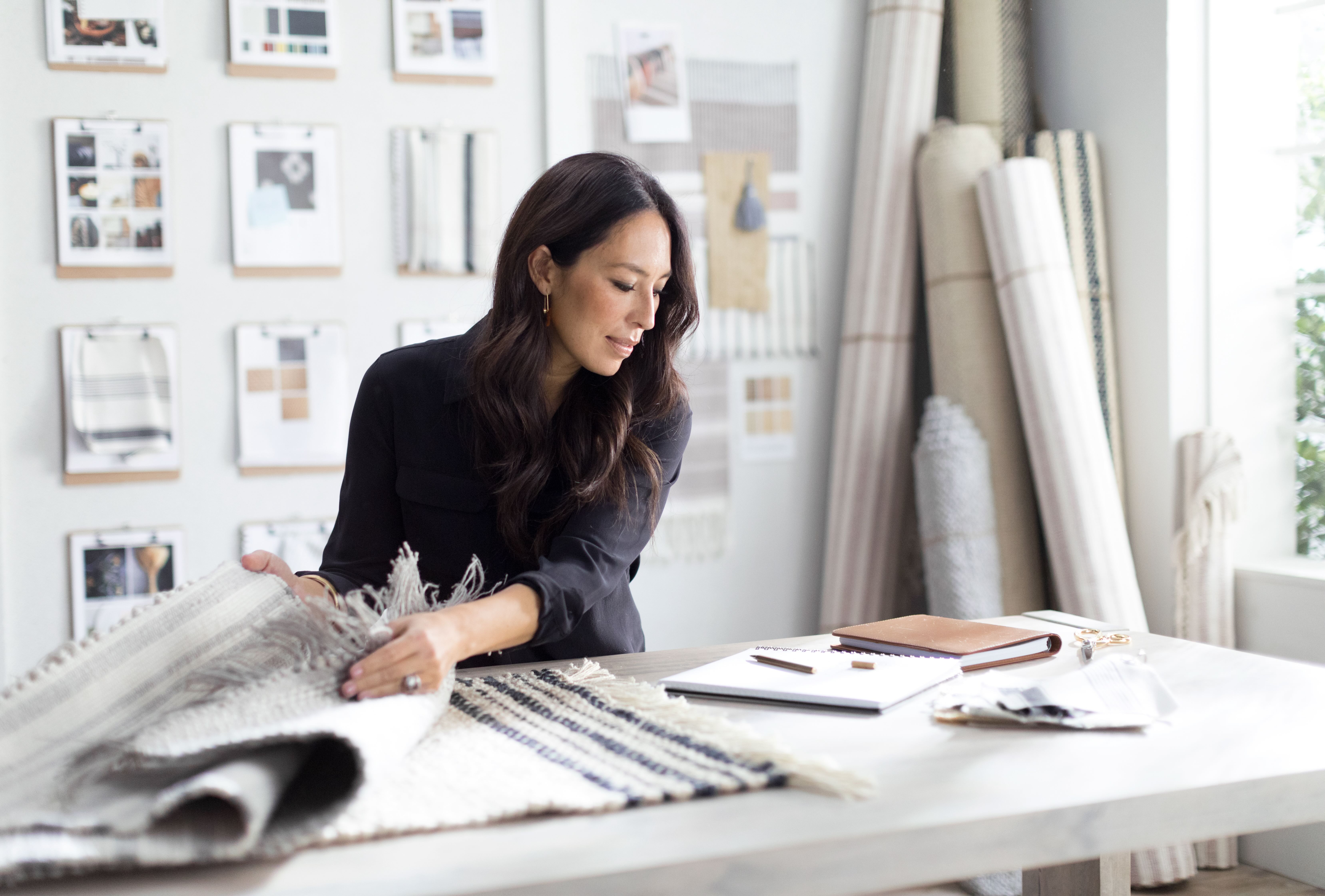 Joanna Gaines reviewing design materials on a tabletop. 