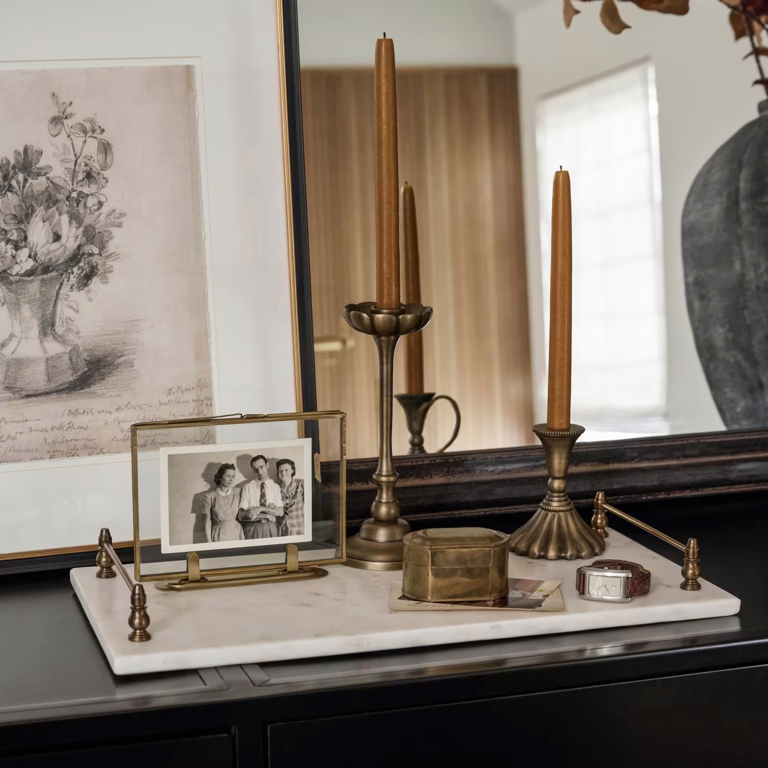 Vintage-looking tray, photo, candles, and mirror on table