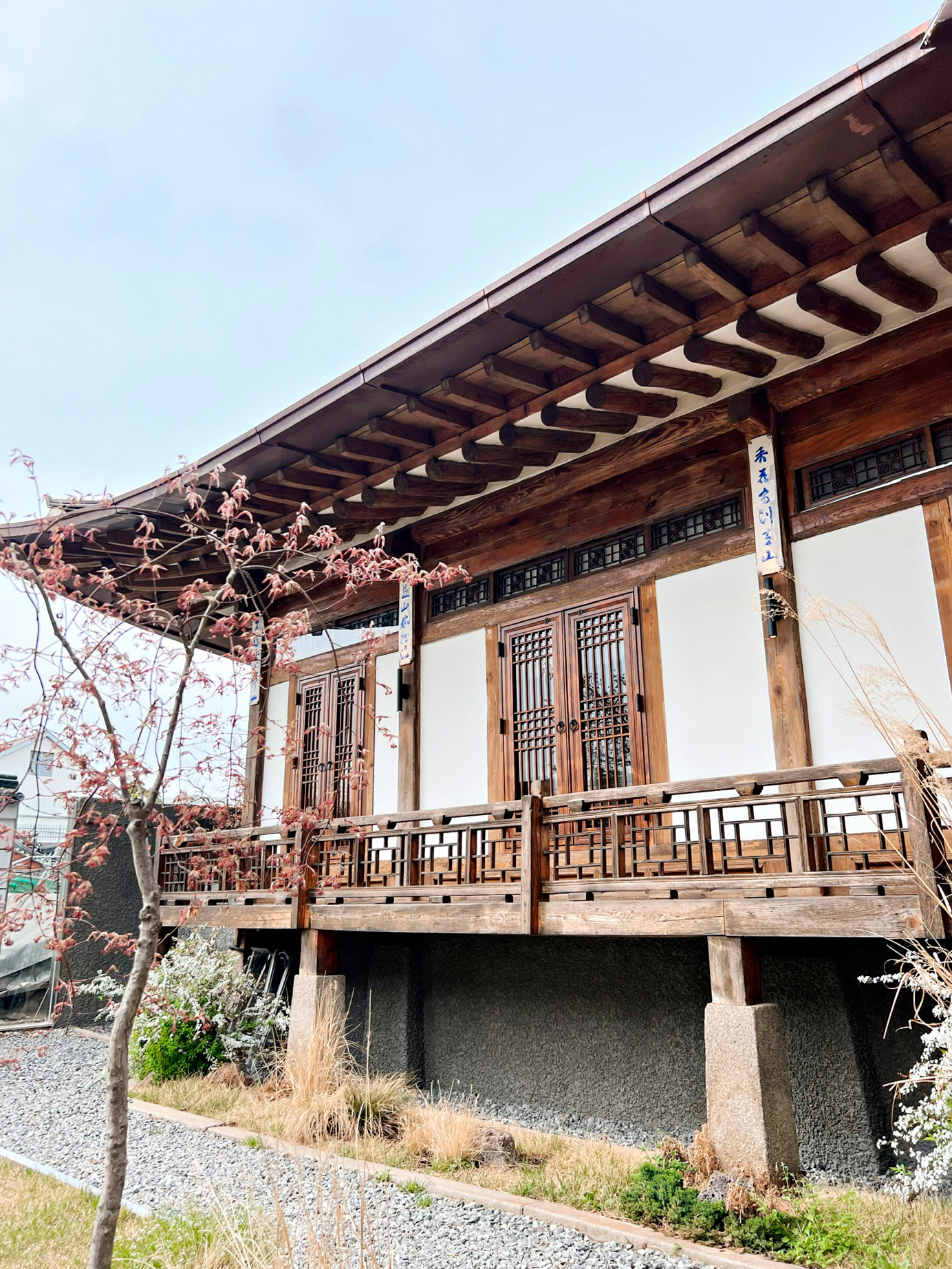 A wooden structure in South Korea, surrounded by grass and blossoming trees.