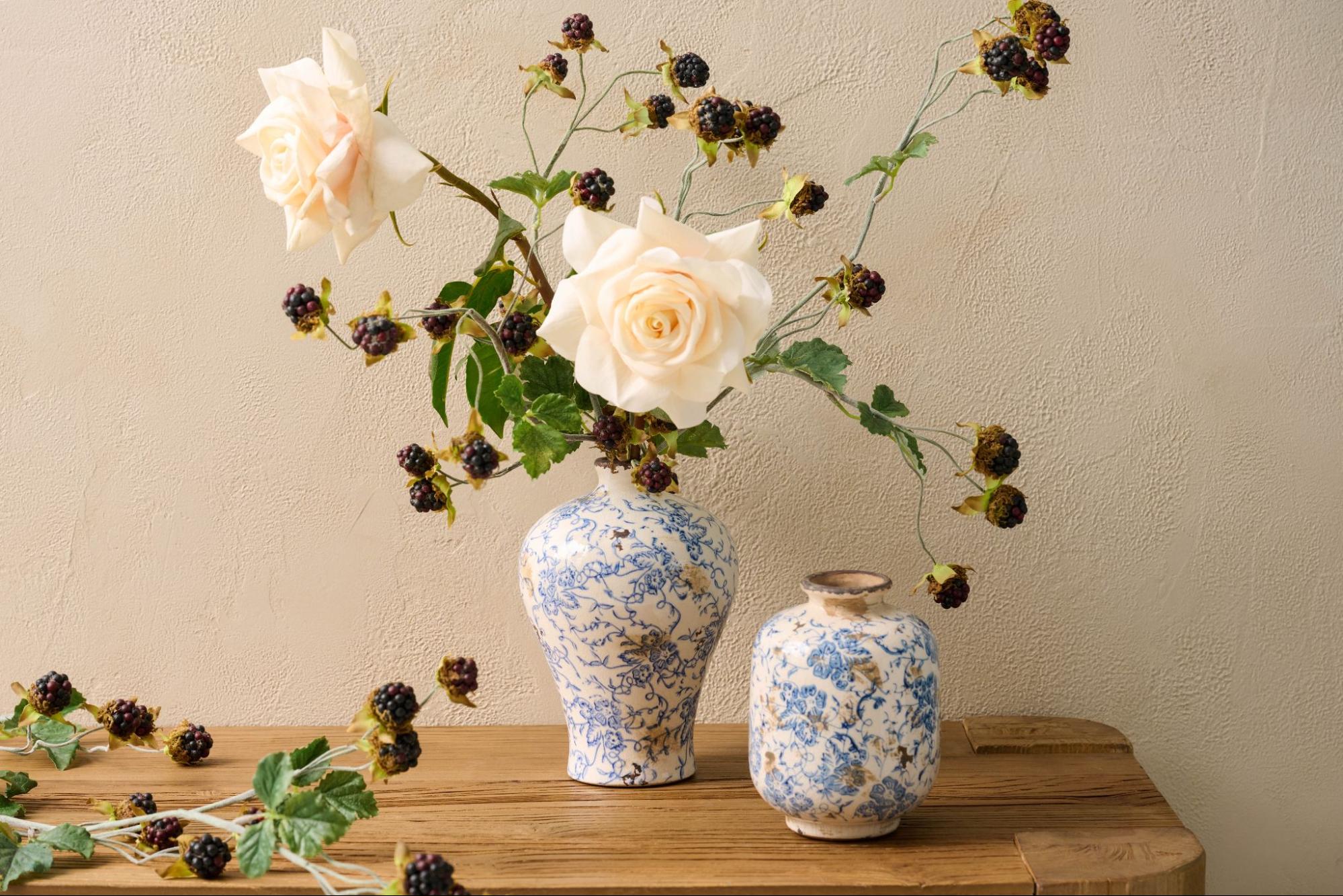 Roses and berry stems sitting inside a blue and white crackle vase from Magnolia. 