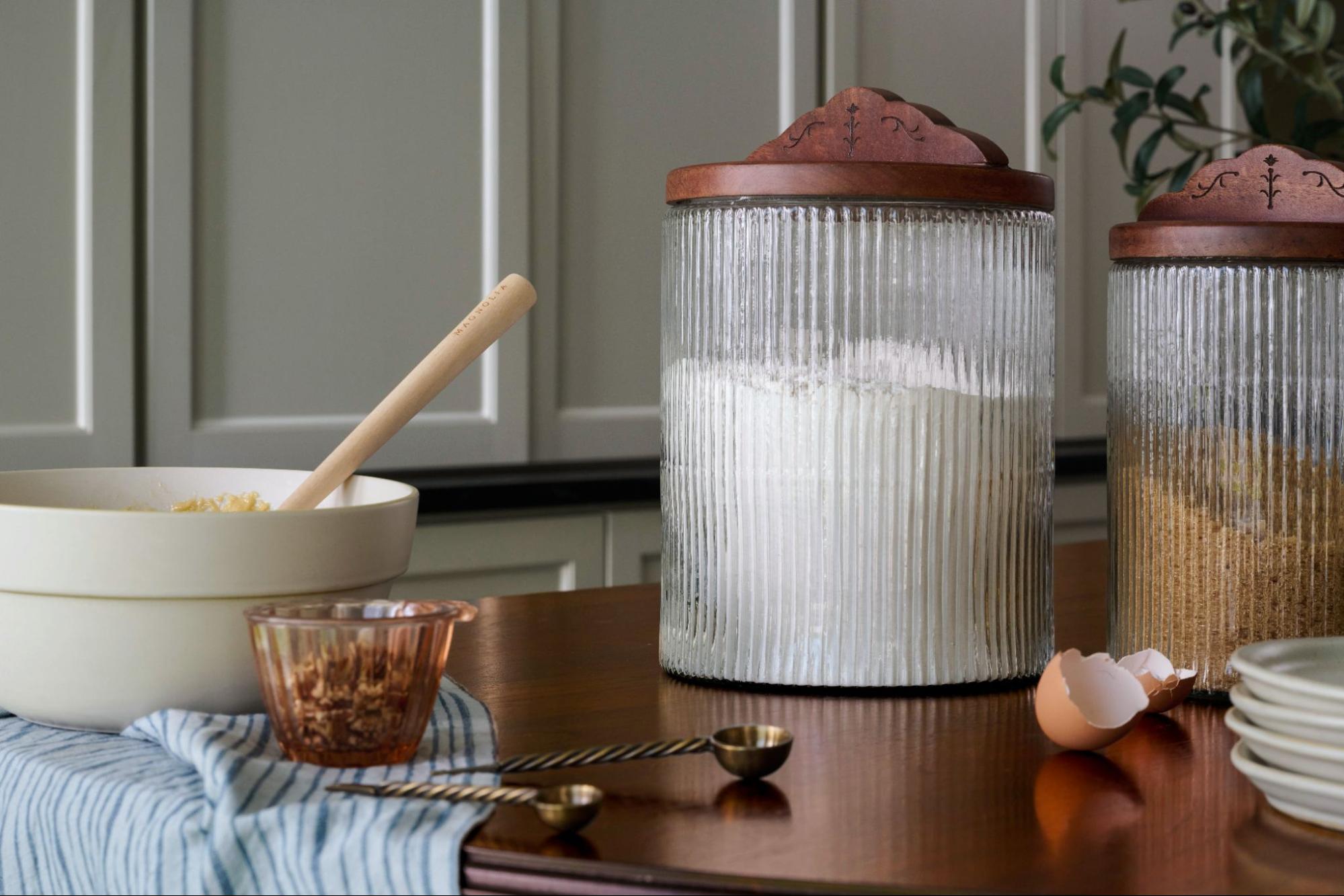 Large canister of flour and other baking supplies on a wooden table