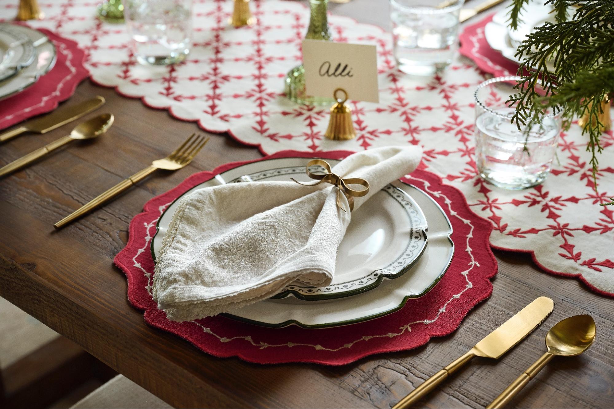 A stack of plates sits on a placemat, topped with a napkin folded in a bow napkin ring.